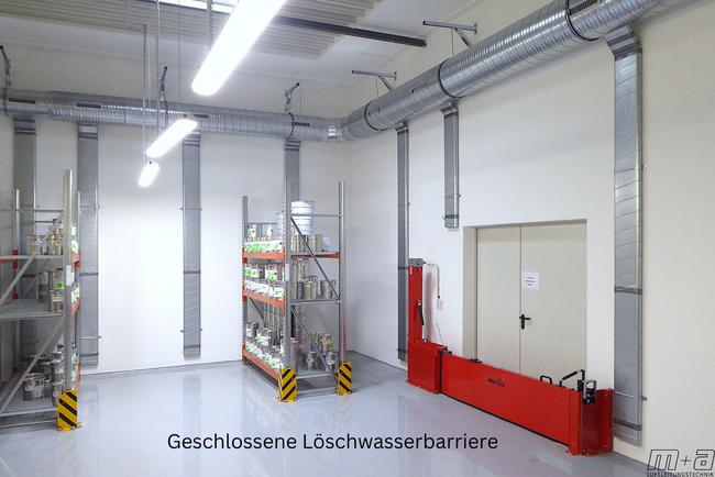 Blick in das Lacklager. Oben an der Decke an der Wand hängen runde Luftleitungen. aus diesen runden Luftleitungen sind ovalrohre, die senkrecht an der Wand hängen. Rechts ist eine 