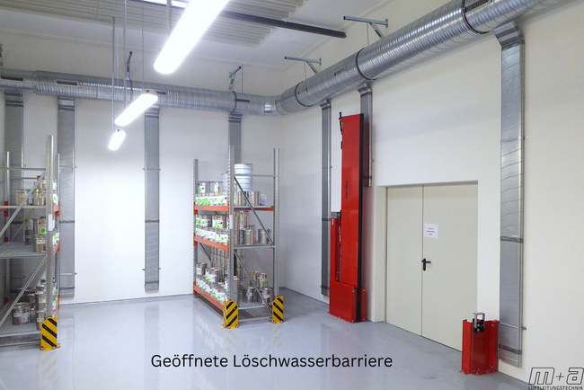 Blick in das Lacklager. Oben an der Decke an der Wand hängen runde Luftleitungen. aus diesen runden Luftleitungen sind ovalrohre, die senkrecht an der Wand hängen. Rechts ist eine 