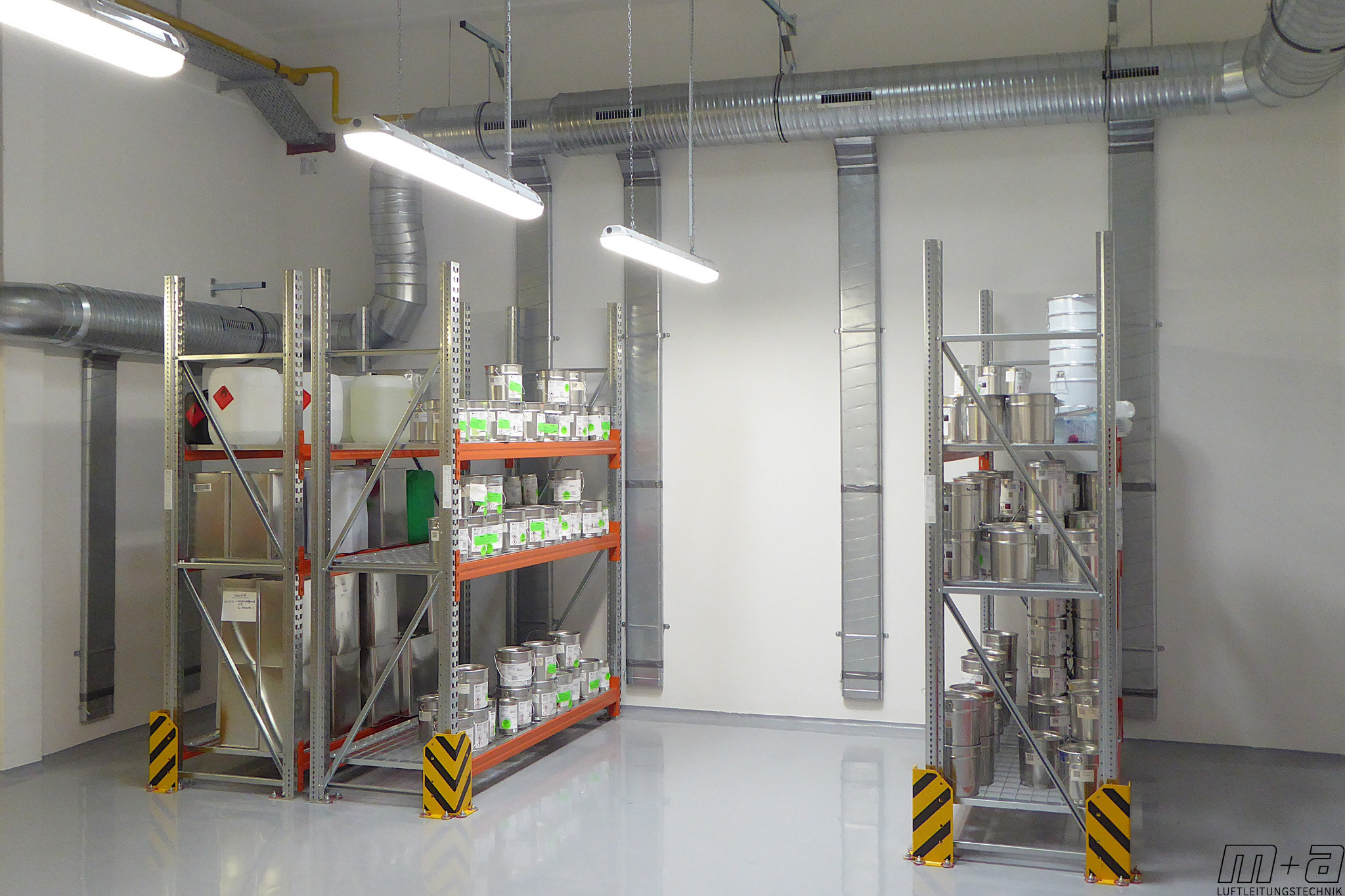 Ovalrohre für technische Lüftung Blick in das Lacklager. Oben an der Decke an der Wand hängen runde Luftleitungen. aus diesen runden Luftleitungen sind ovalrohre, die senkrecht an der Wand hängen. Es stehen Lagergerüste aus Stahl. Auf denen stehen Lacke.